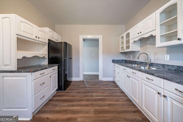 kitchen featuring black refrigerator, white cabinetry, dark hardwood / wood-style floors, and sink