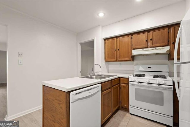 kitchen featuring white appliances, kitchen peninsula, and sink