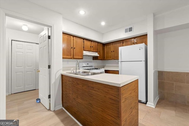 kitchen with white appliances, kitchen peninsula, and sink