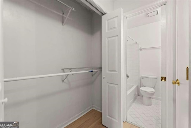 bathroom with shower / tub combination, wood-type flooring, and toilet