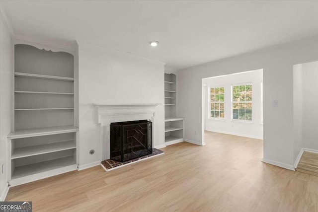 unfurnished living room featuring built in shelves and light wood-type flooring