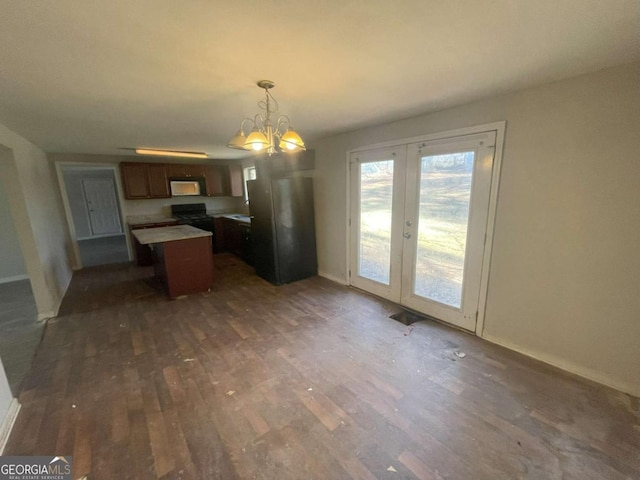 kitchen with decorative light fixtures, dark wood-type flooring, a chandelier, french doors, and a kitchen island