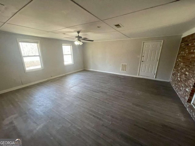 spare room featuring ceiling fan, dark hardwood / wood-style floors, and brick wall