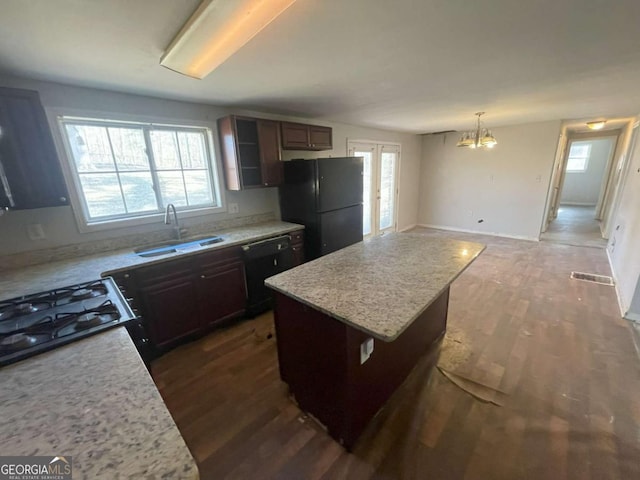 kitchen featuring a kitchen island, black appliances, sink, hanging light fixtures, and a chandelier