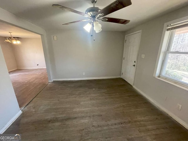 spare room featuring dark hardwood / wood-style flooring and ceiling fan with notable chandelier