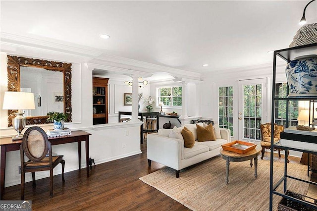 living room with a wealth of natural light, crown molding, dark hardwood / wood-style flooring, and ornate columns