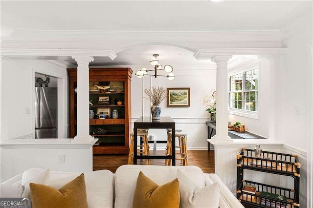 dining area featuring dark wood-type flooring, ornamental molding, and a notable chandelier