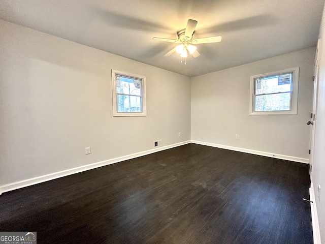 empty room with ceiling fan and dark wood-type flooring