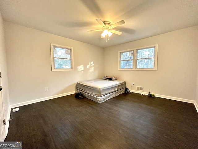 unfurnished bedroom featuring ceiling fan and dark hardwood / wood-style floors