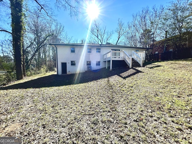 back of property with a wooden deck and a lawn