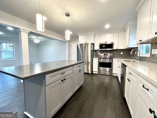 kitchen with a kitchen island, sink, white cabinetry, hanging light fixtures, and stainless steel appliances