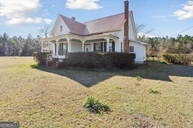 view of side of home with a porch and a yard