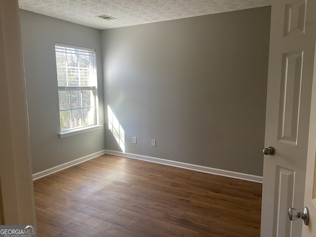 unfurnished room featuring wood-type flooring, a textured ceiling, and a healthy amount of sunlight