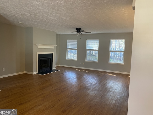 unfurnished living room with ceiling fan, a textured ceiling, and dark hardwood / wood-style floors