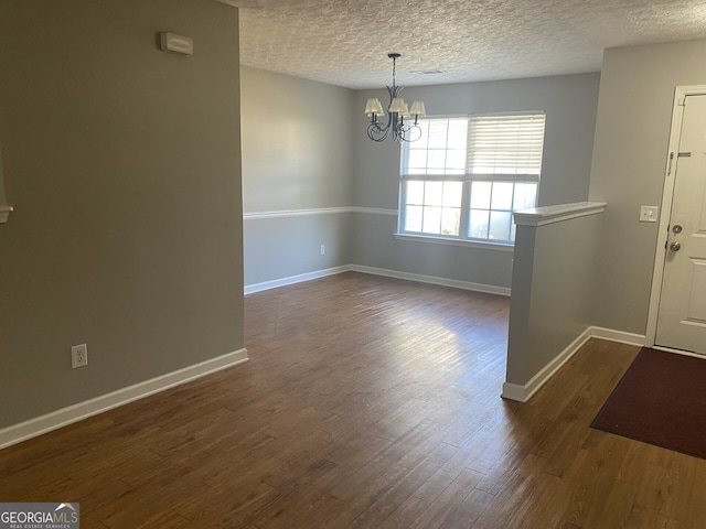 unfurnished dining area featuring a textured ceiling, dark hardwood / wood-style floors, and a chandelier