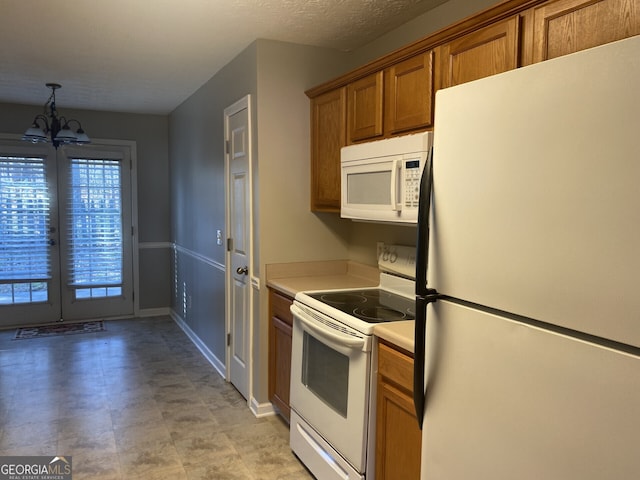 kitchen featuring a notable chandelier, hanging light fixtures, and white appliances