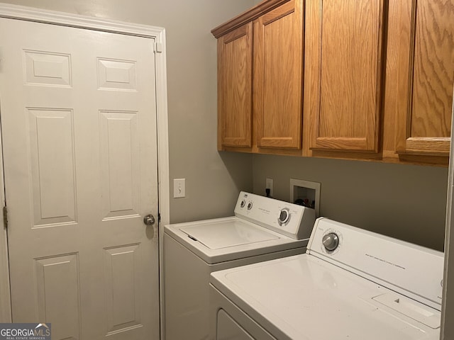 clothes washing area with washer and clothes dryer and cabinets