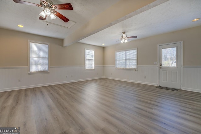 empty room with light wood-type flooring, ceiling fan, and a textured ceiling