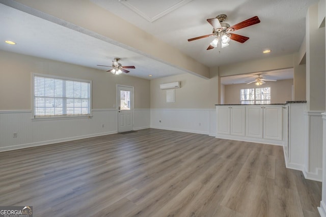 unfurnished living room with light wood-type flooring and a wall unit AC