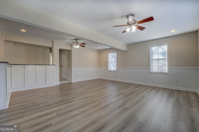 unfurnished room with ceiling fan, a textured ceiling, and light hardwood / wood-style floors