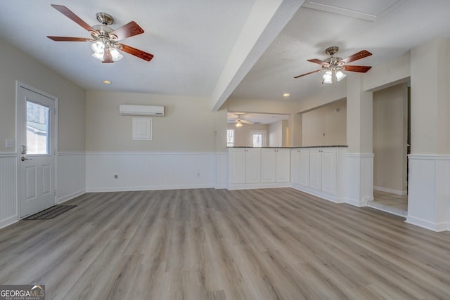 unfurnished living room with light hardwood / wood-style floors and a wall unit AC