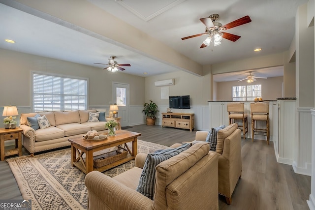 living room featuring a wealth of natural light, wood-type flooring, and a wall mounted air conditioner