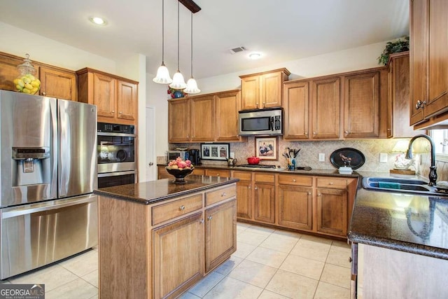 kitchen with appliances with stainless steel finishes, backsplash, decorative light fixtures, a kitchen island, and sink