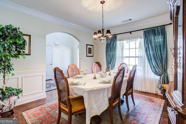 dining space featuring an inviting chandelier, ornamental molding, and dark hardwood / wood-style flooring