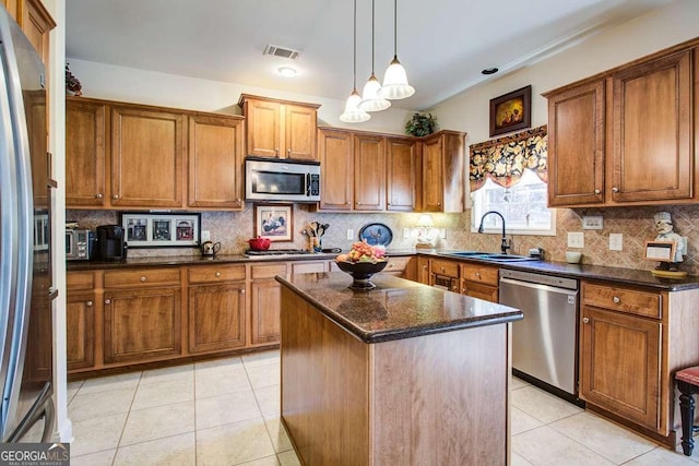 kitchen featuring a center island, stainless steel appliances, dark stone countertops, sink, and light tile patterned floors