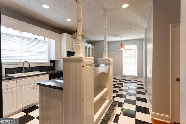 kitchen featuring decorative light fixtures, dishwasher, sink, a textured ceiling, and white cabinets