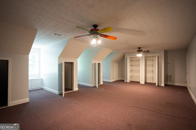 additional living space featuring ceiling fan, dark carpet, a textured ceiling, and vaulted ceiling