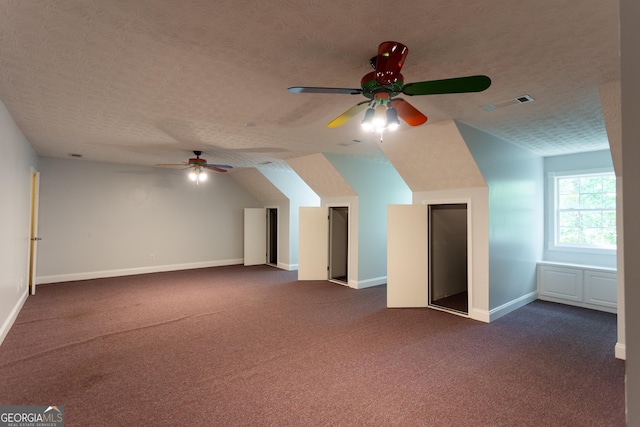 bonus room featuring a textured ceiling, ceiling fan, lofted ceiling, and dark carpet