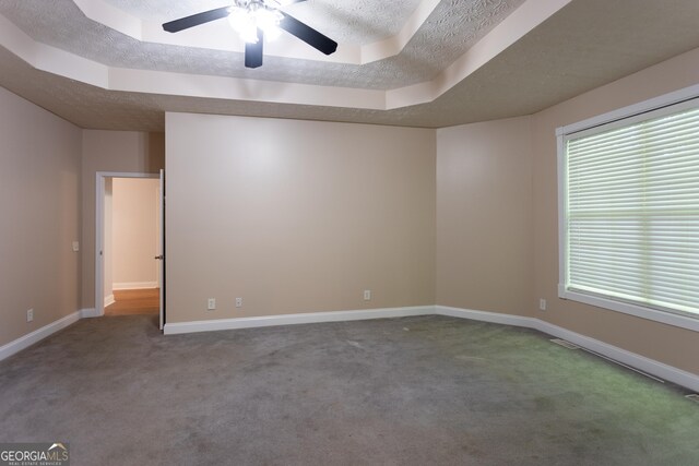 spare room featuring ceiling fan, a tray ceiling, and carpet flooring