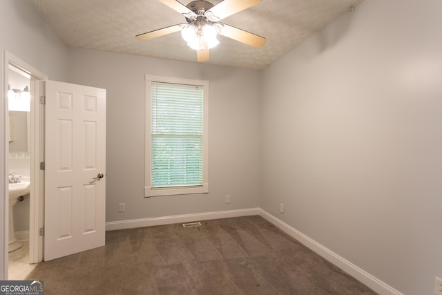 carpeted empty room featuring ceiling fan and a textured ceiling