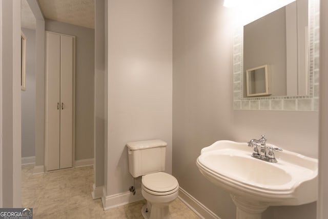 bathroom with a textured ceiling, toilet, and sink