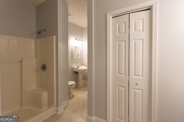 bathroom featuring a shower, a textured ceiling, and toilet