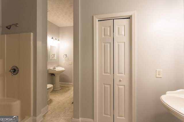 bathroom featuring a shower, sink, a textured ceiling, and toilet