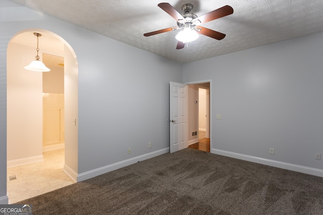 carpeted spare room with ceiling fan and a textured ceiling