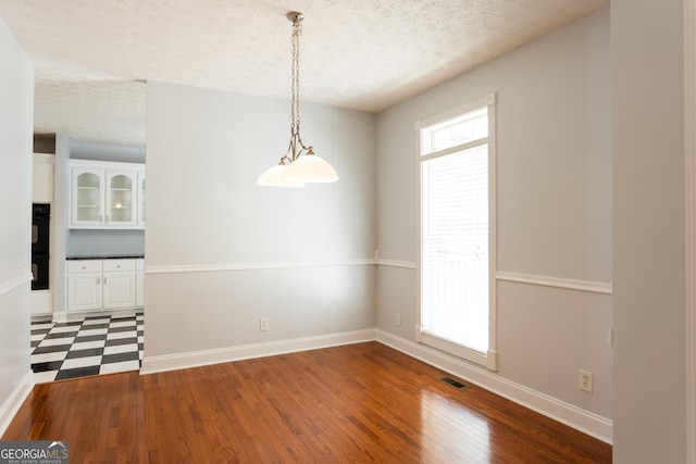 spare room featuring a textured ceiling and dark wood-type flooring