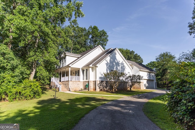 view of front of property with covered porch, a front yard, and a garage