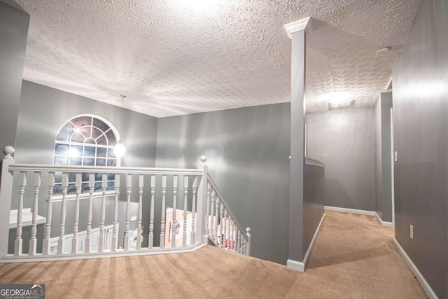 hallway with a textured ceiling and carpet flooring