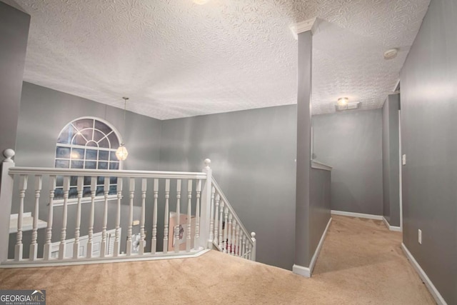 hall with a textured ceiling and carpet floors