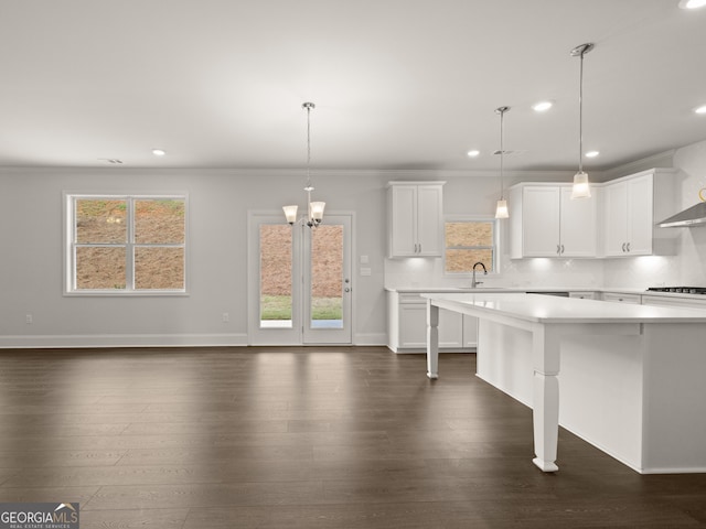 kitchen with white cabinetry, ornamental molding, and decorative light fixtures