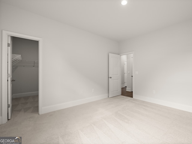 unfurnished bedroom featuring a spacious closet, a closet, and carpet flooring