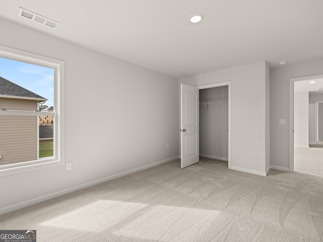 unfurnished bedroom with a closet, light colored carpet, and multiple windows