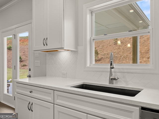 kitchen with a wealth of natural light, backsplash, white cabinets, and sink