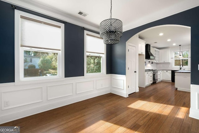 kitchen with stainless steel range, white cabinetry, hanging light fixtures, and custom range hood