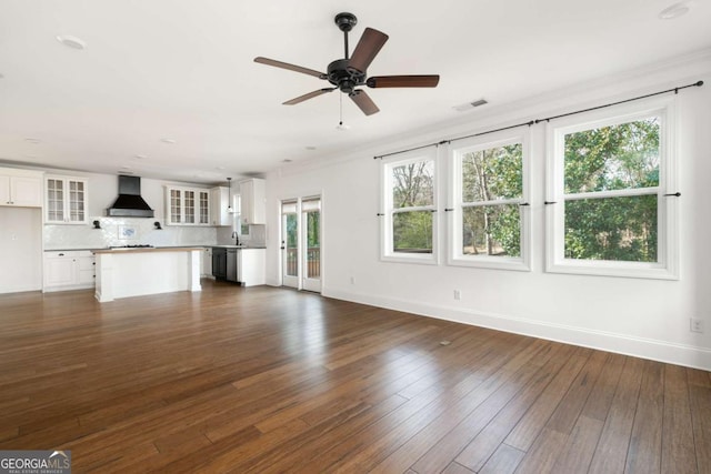 unfurnished living room featuring dark wood-type flooring, ceiling fan, plenty of natural light, and crown molding