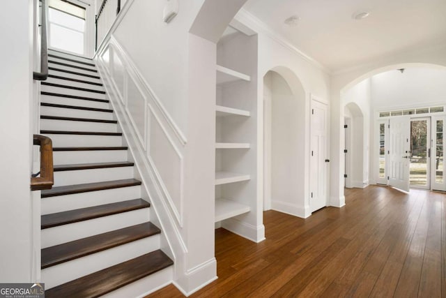 stairway with hardwood / wood-style flooring, built in shelves, ornamental molding, and french doors