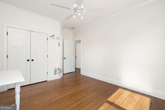 unfurnished bedroom featuring ceiling fan, hardwood / wood-style flooring, a closet, and crown molding